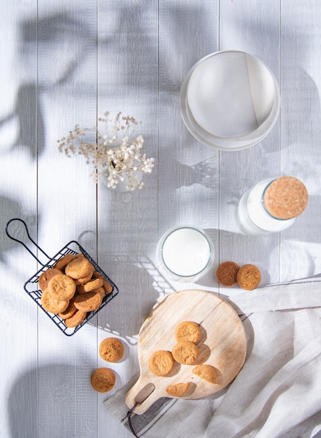 Ochtend verse zelfgemaakte havermoutkoekjes op snijplank met glas melk op een witte houten tafel