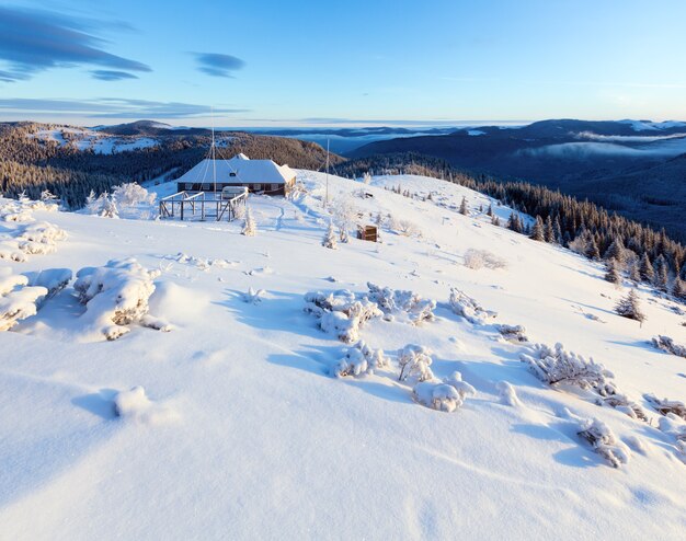 Ochtend winter berglandschap met sneeuw bedekte bomen en huis op nok