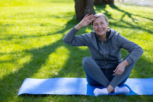 Foto ochtend yoga volwassen vrouw in grijs sportwera doet yoga in het park