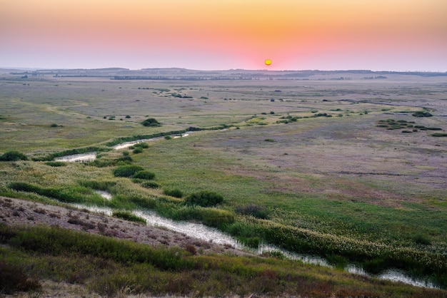 Ochtend zomerlandschap met zonsopgang boven de vallei van de steppe-rivier