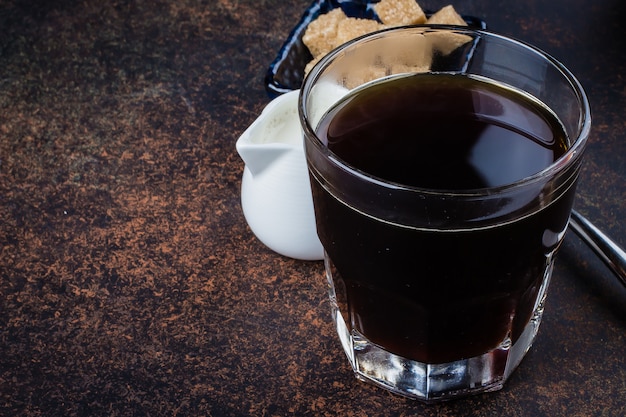 Ochtendbeker warme koffie met melk en suiker op donkere steen concrete achtergrondlijst. Ruimte kopiëren