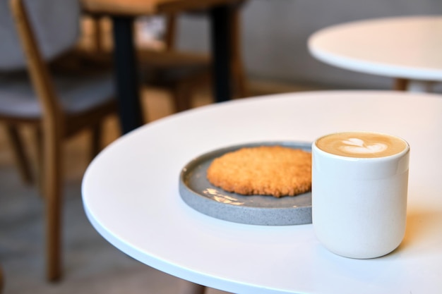 Ochtendbrunch in café staat op tafel Gigantisch koekje en cappuccino met prachtig melkschuim even pauze