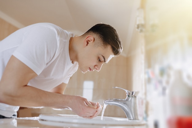 Ochtendhygiëne, de jongen wordt gewassen in een wasbak met waternevel