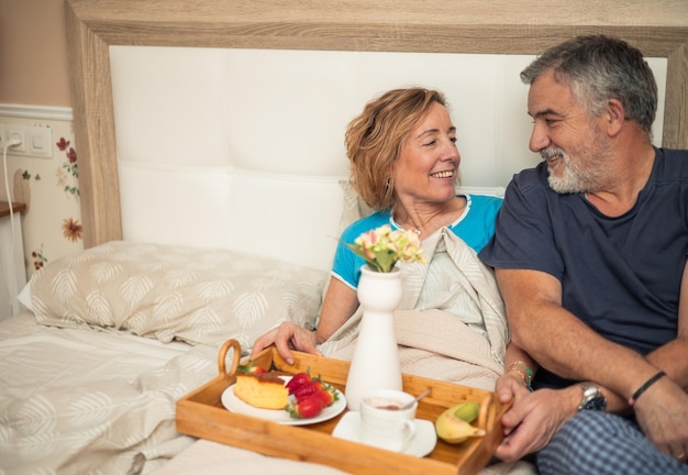 Foto ochtendliefde bejaard echtpaar geniet samen van het ontbijt in bed