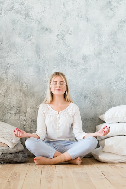 Ochtendmeditatie. Levensstijl concept. Jonge vrouw zittend op de vloer met gekruiste benen met mudra gebaar.