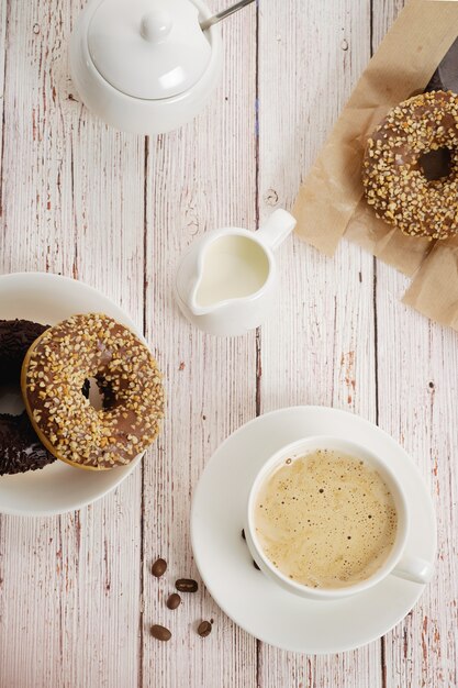 Ochtendontbijt met chocoladedoughnuts en kop van koffie met room. Heerlijke donuts bestrooid met gemalen noten. bovenaanzicht