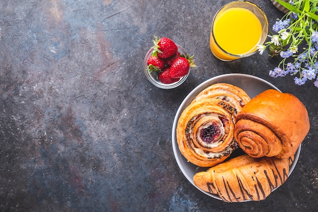 Ochtendontbijt met jus d'orange, aardbei en broodjes. Bovenaanzicht, tekstruimte