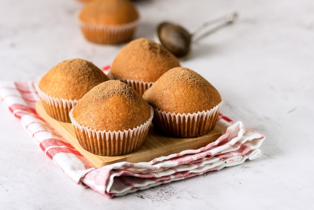 Ochtendontbijt Vanille Muffins in witte papieren bekers op houten snijplank grijze achtergrond