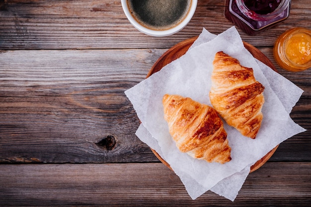 Ochtendontbijt Zelfgemaakte gebakken croissants met jam en koffie op houten rustieke achtergrond Bovenaanzicht