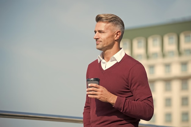 Ochtendpauze Blanke man drinkt koffie in de ochtend Knappe man houdt afhaalmaaltijden buiten vast Goedemorgen gewoonte routine Ochtend in de stad