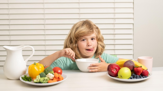 Ochtendsnack met muesli granen muesli Kid preteen jongen in de keuken aan de tafel groente en fruit eten tijdens het diner lunch Gezonde voeding groenteschotel voor kinderen