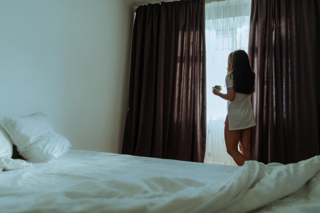 Ochtendvrouw wordt wakker, schuif de gordijnen uit om de zon de kamer binnen te laten