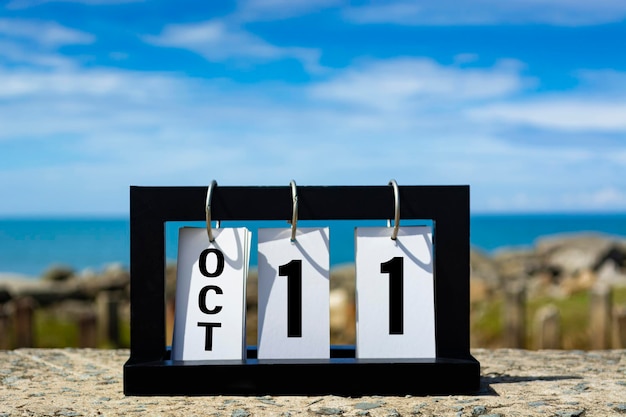 Foto 11 ottobre testo di data di calendario su cornice di legno con sfondo sfocato dell'oceano concetto di data di calendario