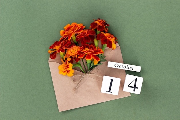 October 14 Bouquet of orange flower in craft envelope and calendar date on green background Minimal concept Hello fall Template for your design greeting card