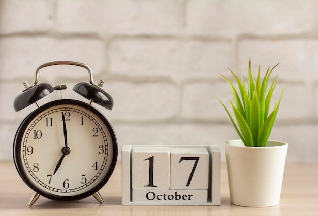 October 17 on a wooden calendar next to the alarm clock the date of the autumn month