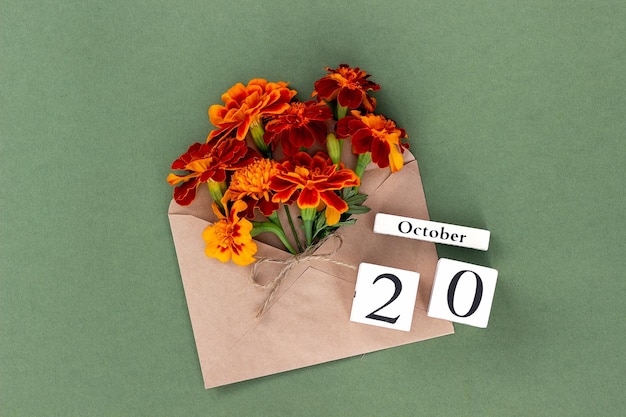 October 20 Bouquet of orange flower in craft envelope and calendar date on green background Minimal concept Hello fall Template for your design greeting card