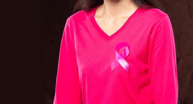 October breast cancer awareness month adult woman in pink shirt\
hand holding pink ribbon for supporting people living and illness\
international women mother and world cancer day concept copy\
space