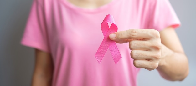 Ottobre mese della consapevolezza del cancro al seno, donna anziana in maglietta rosa con la mano che tiene il nastro rosa per sostenere le persone che vivono e le malattie. concetto di giornata internazionale delle donne, della madre e del cancro del mondo