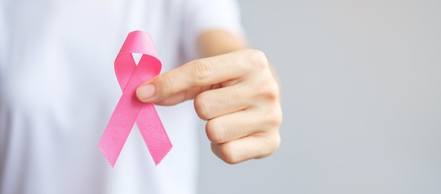 October Breast Cancer Awareness month, elderly Woman in white T- shirt with hand holding Pink Ribbon for supporting people living and illness. International Women, Mother and World cancer day concept