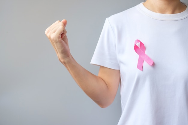 October Breast Cancer Awareness month, elderly Woman in white T- shirt with Pink Ribbon and fist sign for supporting people living and illness. International Women, Mother and World cancer day concept