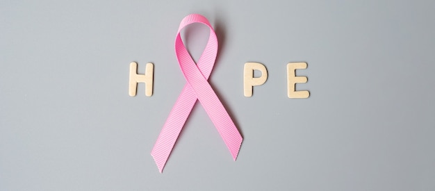 October Breast Cancer Awareness month, Pink Ribbon with HOPE text on grey background for supporting people living and illness. International Women, Mother and World cancer day concept