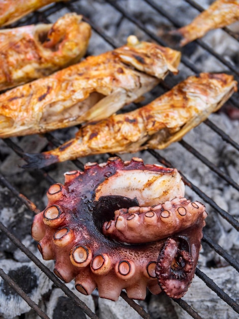 Octopus tentacles and fish with suction cups on grill closeup in Greek island