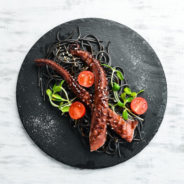 Octopus tentakels gebakken in knoflooksaus en zwarte pasta met inktvisinkt. Luxe restaurant eten. Zeevruchten. Rustieke stijl. Plat leggen.