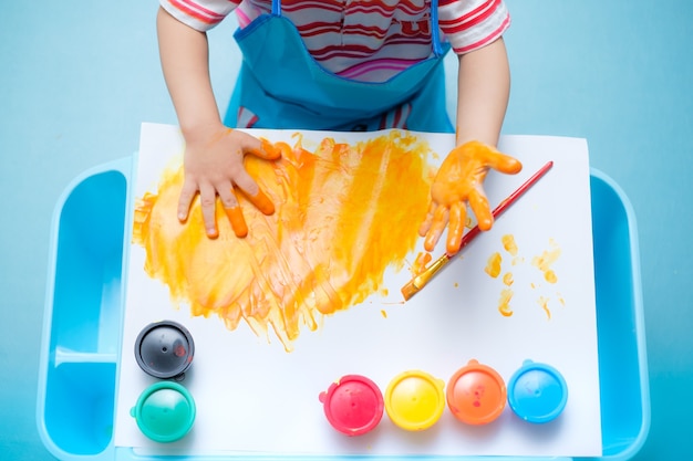 oddler baby boy child finger painting with hands and watercolors