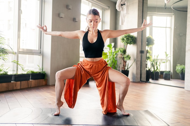 Oefening asana pose in de sportrichting van yoga een flexibele vrouw staat op haar tenen met behulp van een mat