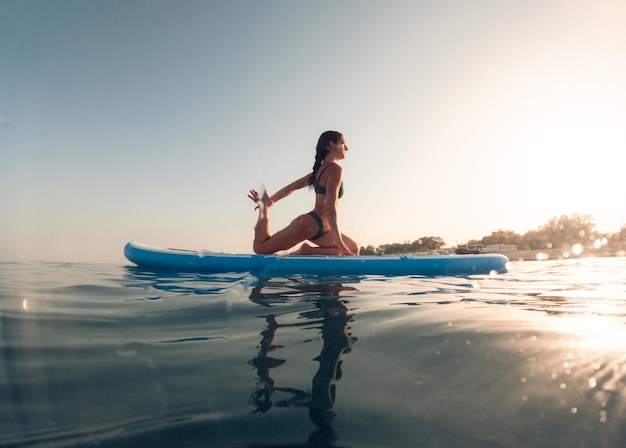oefeningen op een paddle sup board in de oceaan bij zonsopgang