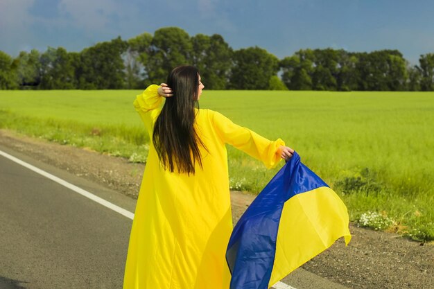 Oekraïens meisje met een blauwgele vlag in haar handen op de achtergrond van het veld