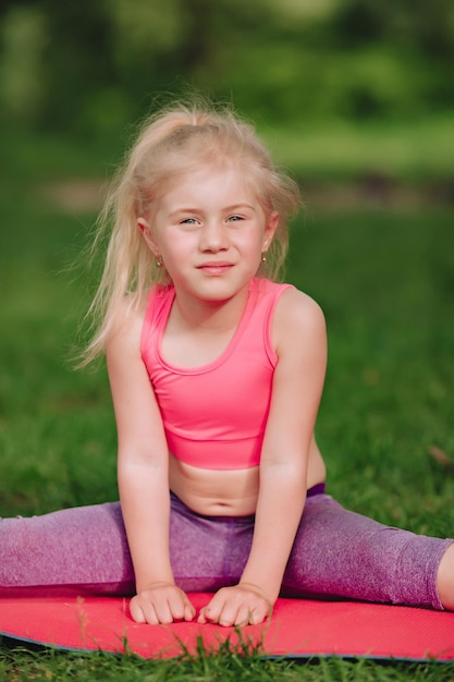 Oekraïens mooi 7-jarig meisje houdt zich bezig met fitness in een groen veld in de buurt van de rivier