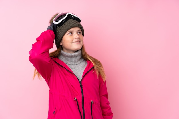 Oekraïens tienerskiërmeisje met snowboarding glazen over het geïsoleerde roze lachen