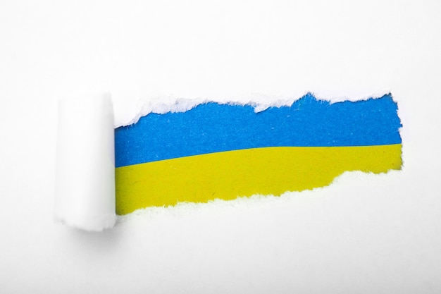 Foto oekraïense blauwe en gele vlag in het gat in papier