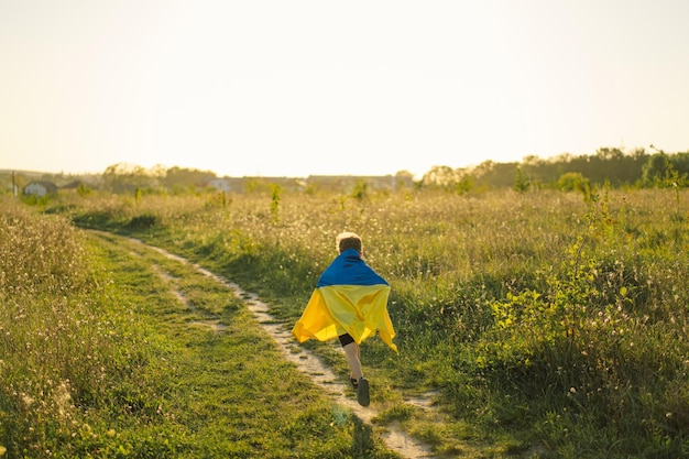 Oekraïense onafhankelijkheidsdag oekraïense kindjongen in wit t-shirt met gele en blauwe vlag van oekraïne in veld vlag van oekraïne grondwetsdag stand met oekraïne