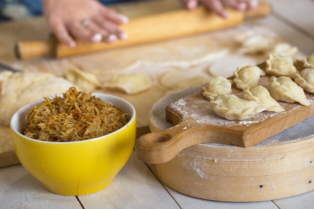 Oekraïense traditionele bakkerijproducten - Pierogies maken door vrouwelijke handen. Rustieke stijl.