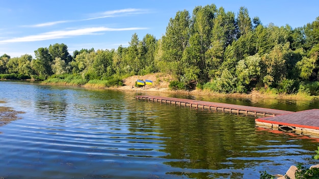 Oekraïense vlaggen wapperen op de pier van de rivier Zonnige zomerdag Symbolen van Oekraïne