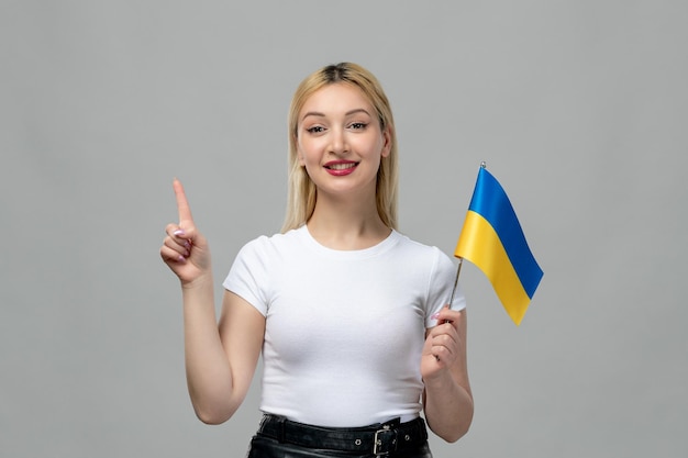 Oekraïne Russisch conflict blond schattig meisje met rode lippenstift en Oekraïense vlag wijzende vinger omhoog