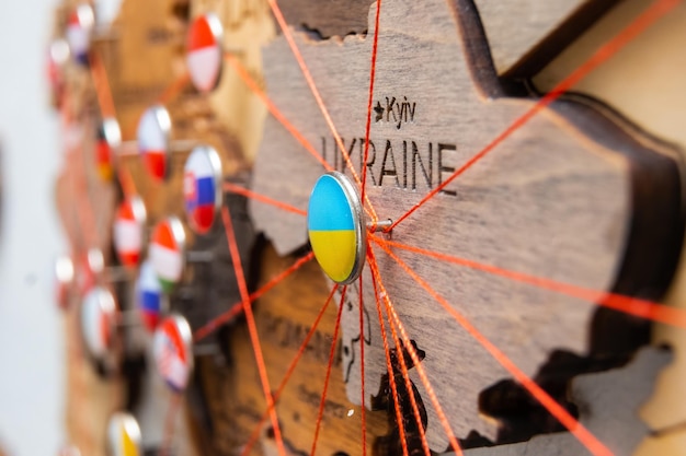 Oekraïne vlag op de punaise en rode draad op de houten kaart close-up