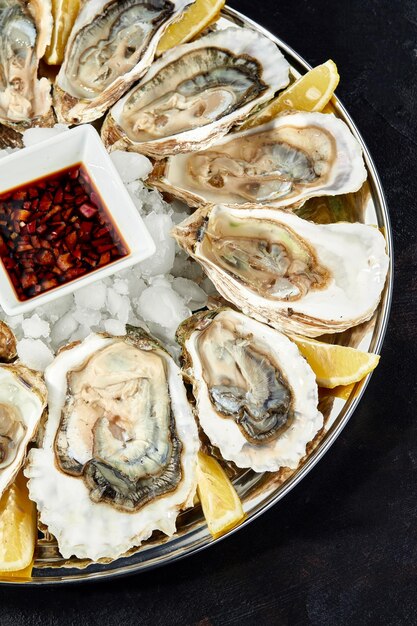 Oesters met citroen geserveerd op zwarte ronde schaal Luxe delicatessen zeevruchten