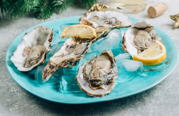 Oesters met citroen, ijs en witte wijn op betonnen ondergrond met een feestelijk decor. kerstdiner