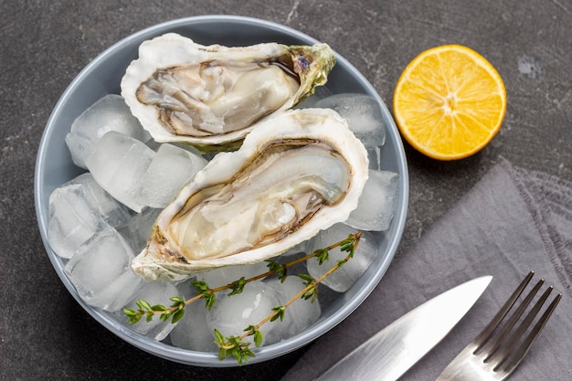 Oesters met ijs in kom Citroen mes en vork op tafel Plat leggen zwarte achtergrond