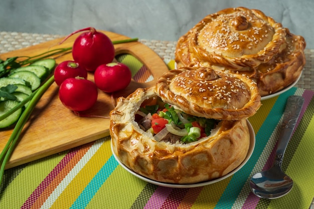 Oezbeekse keuken samsa chorba versierd met groene ui, rode radijs en gesneden komkommer