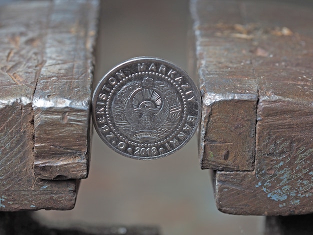 Oezbeekse munt die in een metalen bankschroef is geklemd