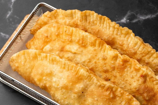 Oezbeekse Oost-Tataarse keuken cheburek op een zwart bord Cheburek gebakken taart met vlees Traditioneel gerecht van Turkse en mongoolse pasteitjes empanada