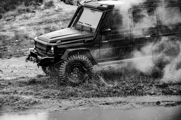 山道の村へのオフロードジープ遠征泥だらけの道で水しぶきを上げて水を渡るクラシックな4x4車オフロード車