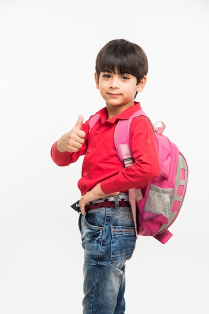 Via a scuola - simpatico ragazzino indiano o asiatico in camicia rossa e jeans denim con borsa da scuola, in piedi isolato su sfondo bianco