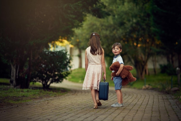 Off to see the world Shot of a little girl and her brother walking away while carrying suitcases and toys