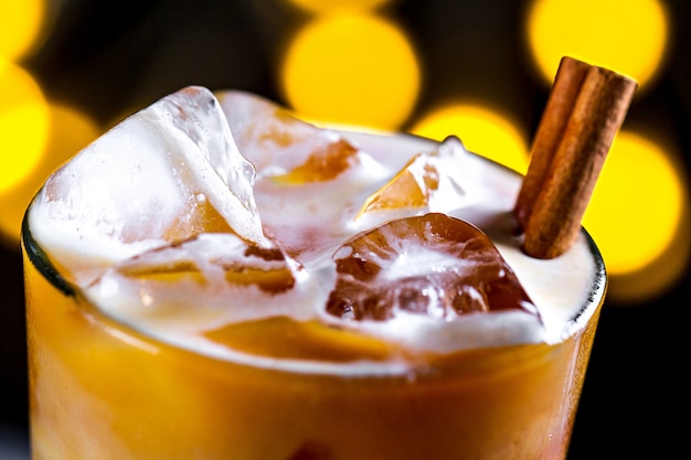 Ð¡offee, refreshing cocktail with ice cubes, foam and cinnamon on the surfce of lights. Cold drinks