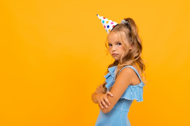 Offended girl in a festive cap stands sideways with folded arms